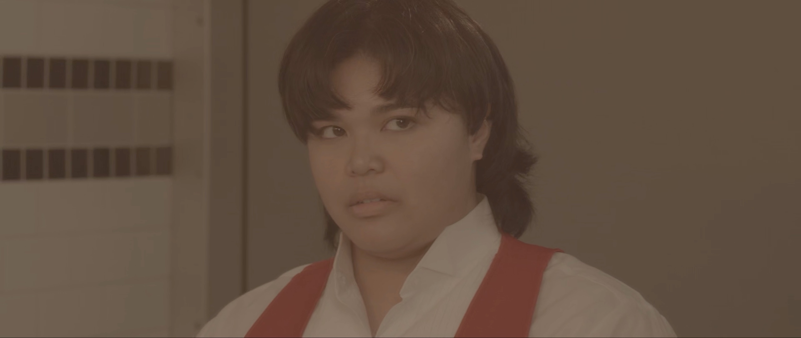 A woman in a white shirt and red suspenders glances warily to one side